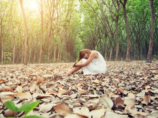 Fotografía de mujer triste sentada en el bosque en otoño